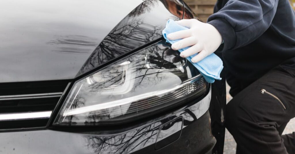 Ein Mann wischt mit Lappen über den Lack eines Autos als Teil einer professionellen Autoreinigung.